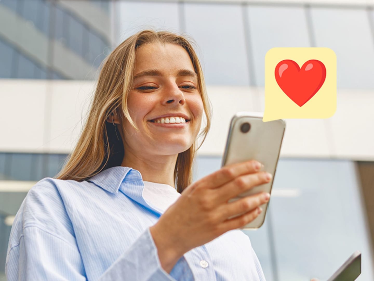 Leende person som tittar på sin mobiltelefon med en hjärtsymbol